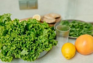 A vibrant display of fresh green lettuce and citrus fruits on a kitchen table.